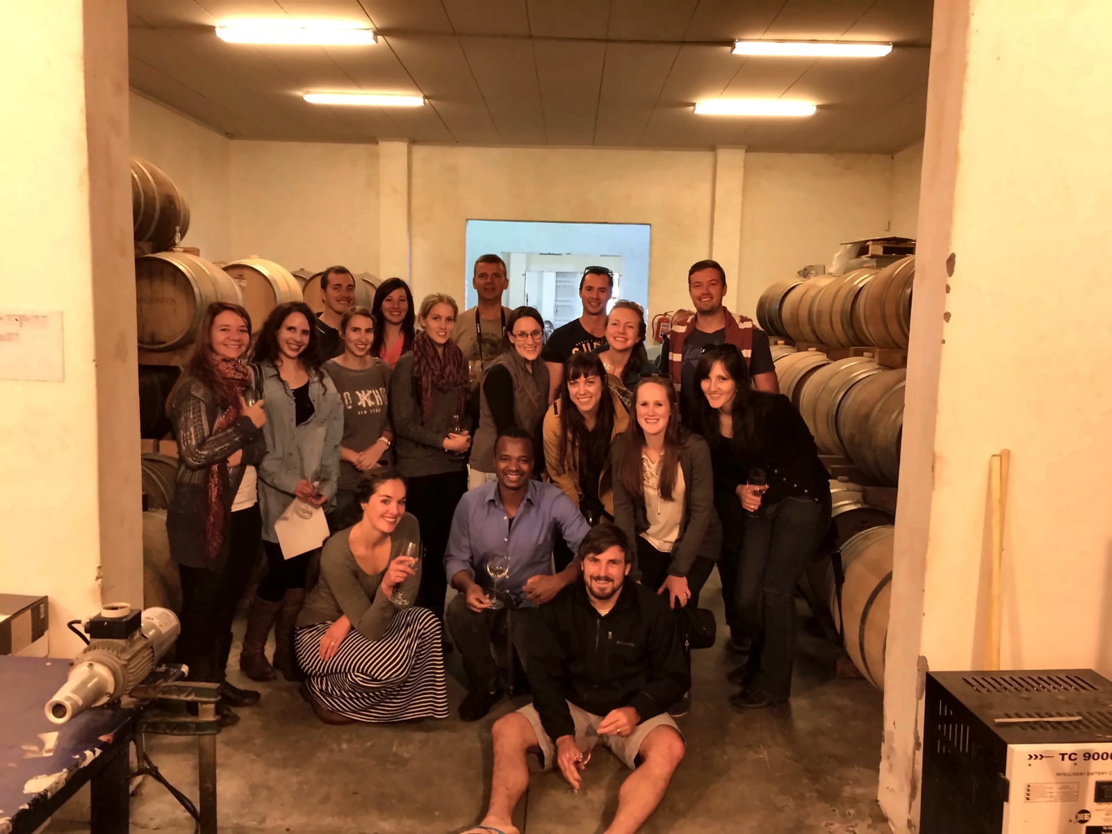 A tasting group gathered among the barrels in a winery cellar