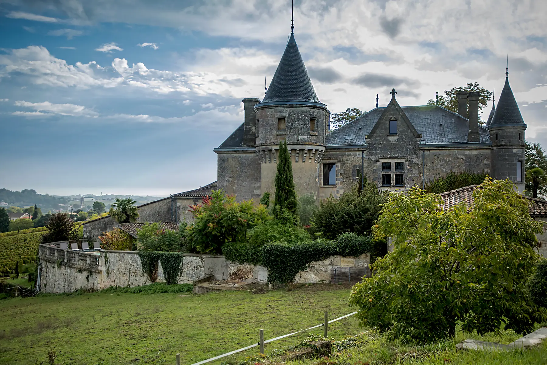 Château de la Grave under a dramatic sky beside a vineyard track
