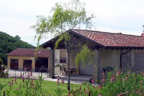A brick farmhouse with a tiled roof behind a flowering garden